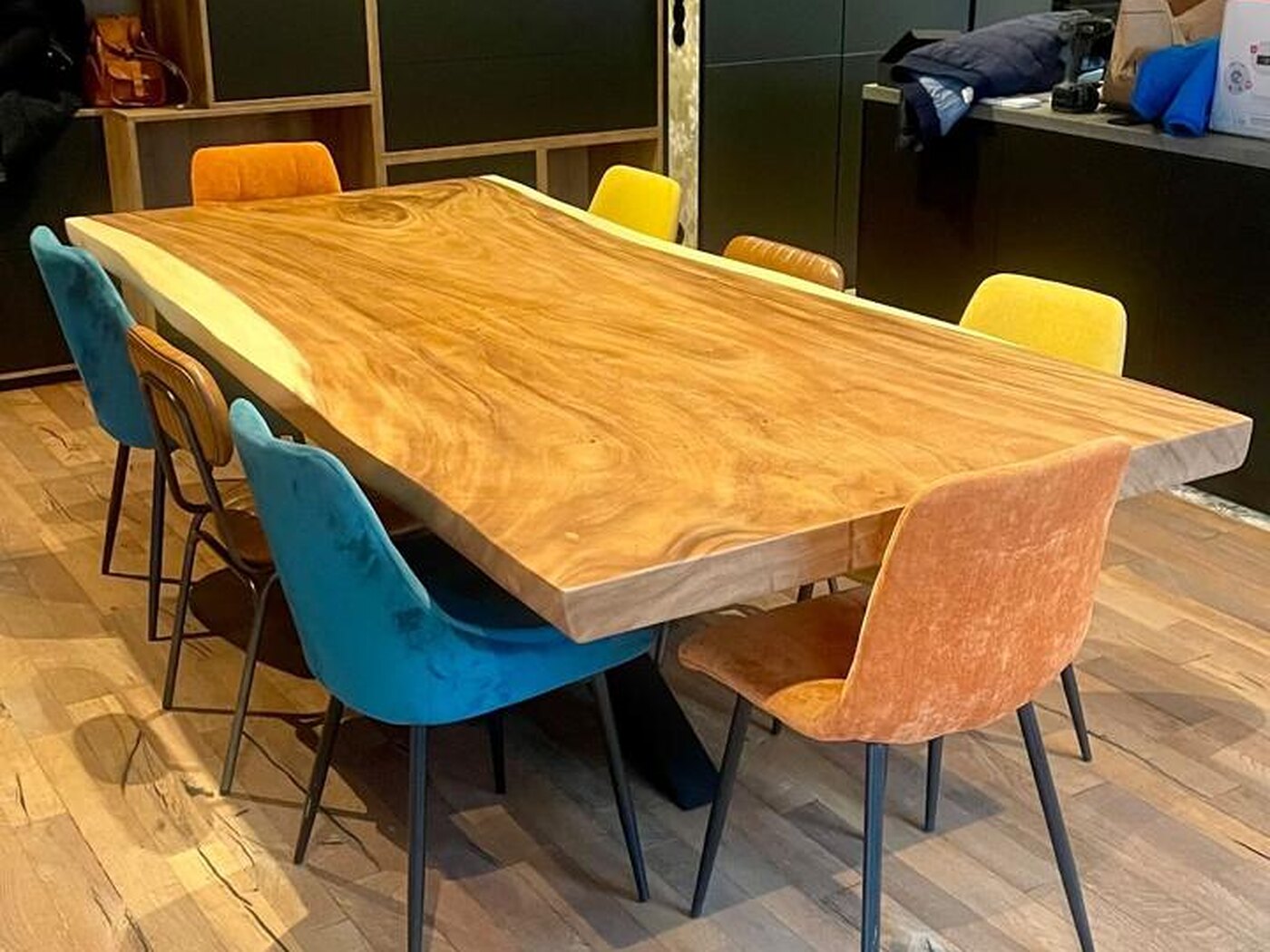 The table along the kitchen, dark full-height joinery and open oak cubbies behind it, rustic oak boards underfoot