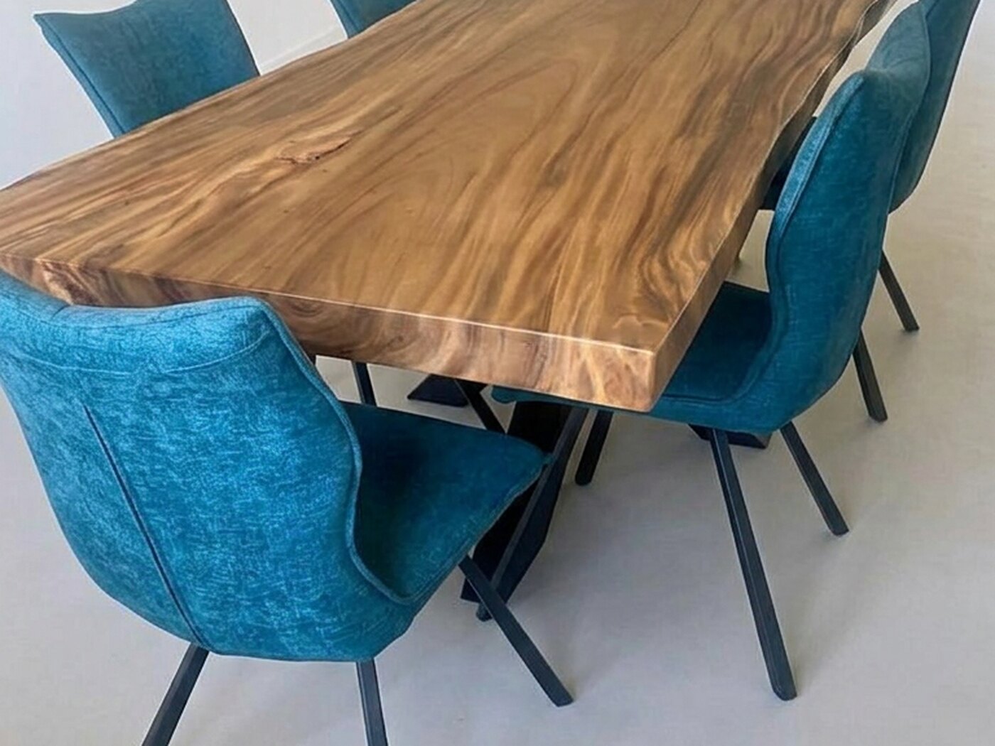 The table from a corner, blue chairs and the splayed black frame beneath