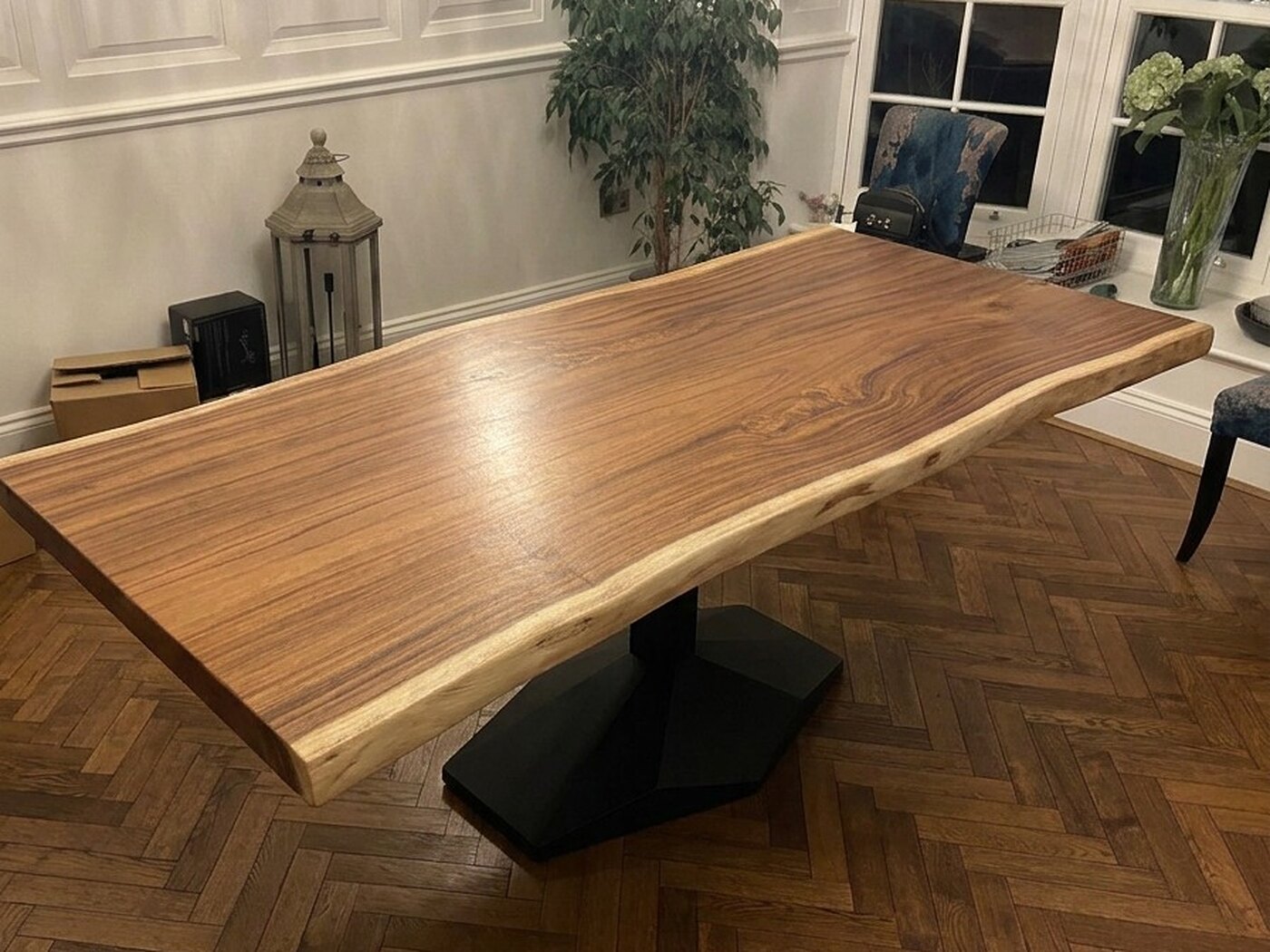 The table from a corner of the room at night, white panelling and a floor lantern behind it and the faceted black pedestal beneath the top