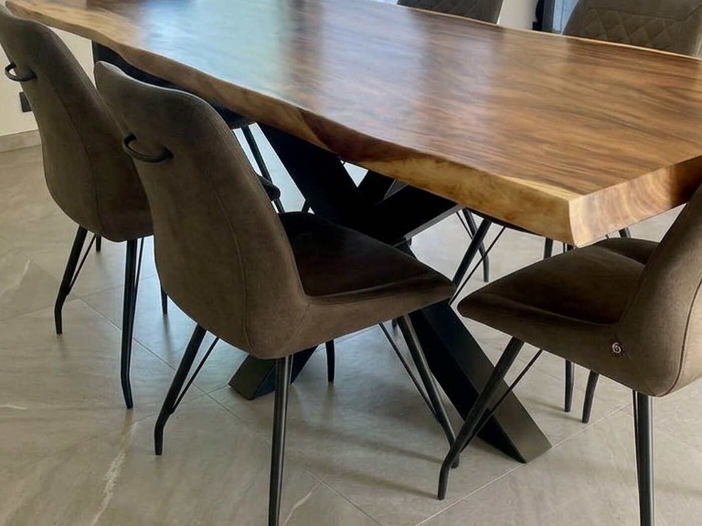 The table seen end-on down its length, chairs drawn in on both sides and daylight across the pale stone floor