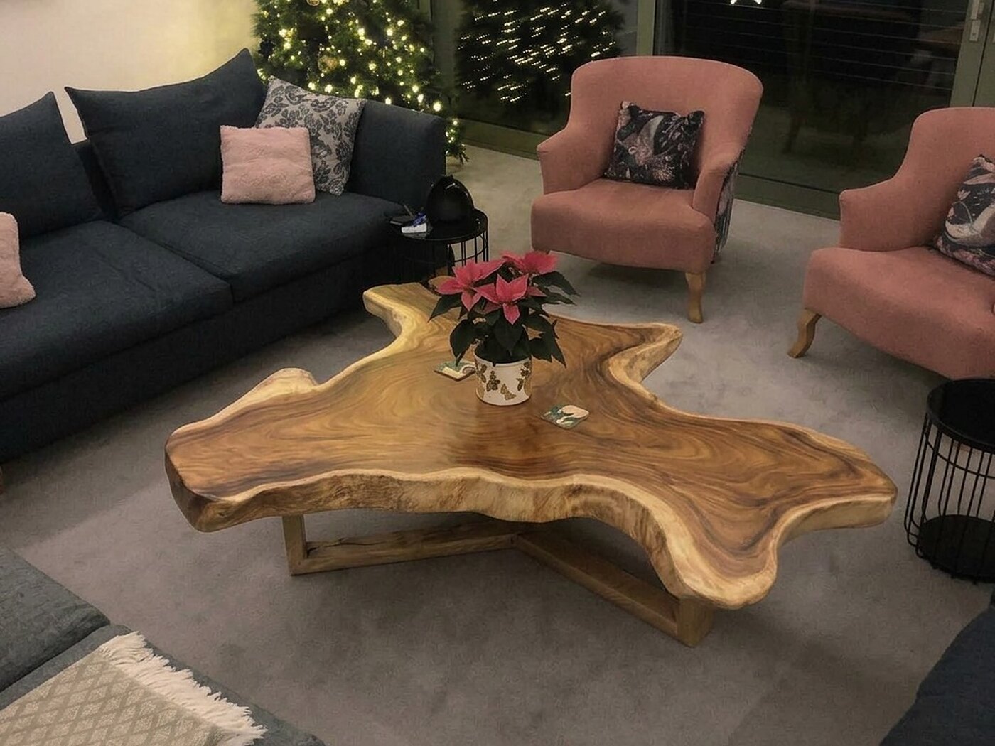 The table from above, the grain swirling honey and dark brown across the top, charcoal sofas and pink armchairs around it