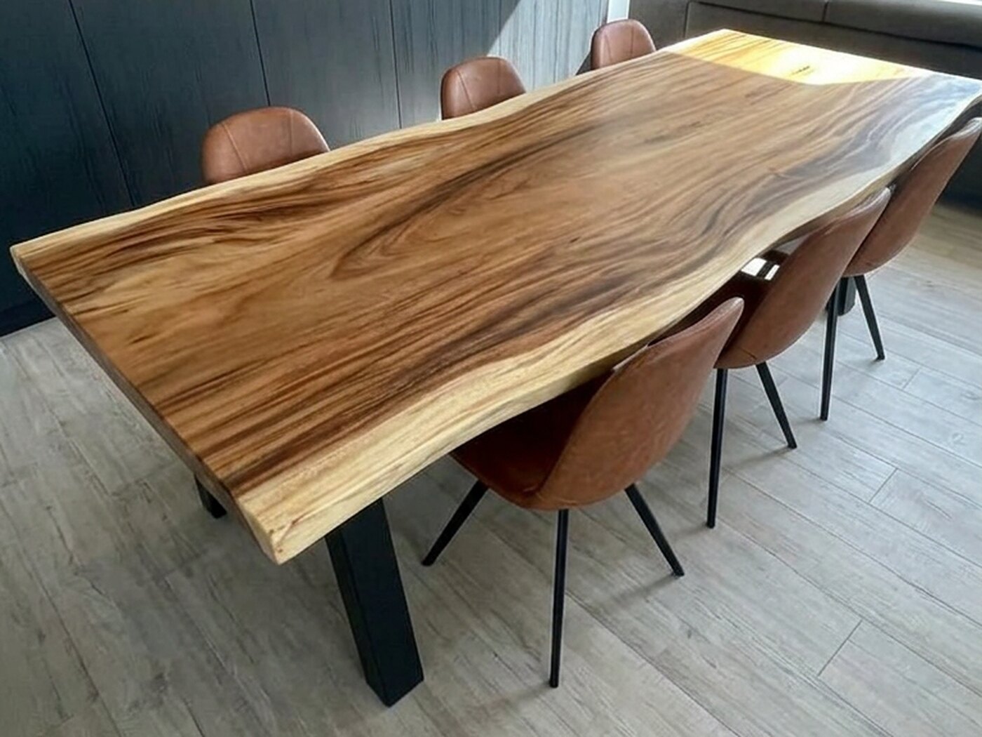 The table down its length beside dark panelling, a window and seating in the room beyond it