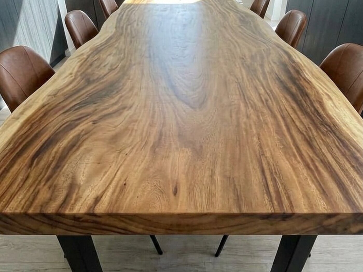The near end of the top with its pale sapwood edge, the black leg dropping away beneath